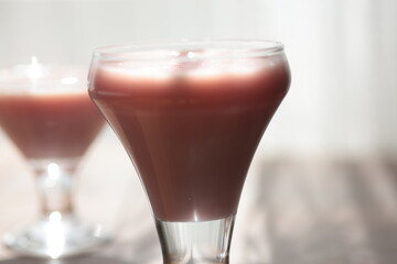 Strawberry pink pudding in glass mug on wooden table close up