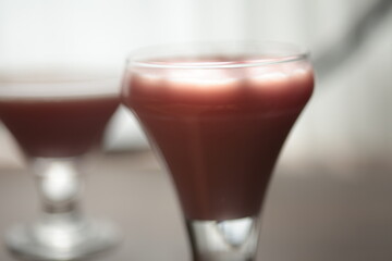 Strawberry pink pudding in glass mug on wooden table close up