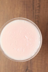 Strawberry pink pudding in glass mug on wooden table close up