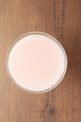 Strawberry pink pudding in glass mug on wooden table close up