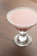 Strawberry pink pudding in glass mug on wooden table close up