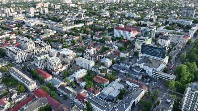 Aerial drone view of central Chișinău, Moldova, showcasing modern buildings, leafy streets, historic architecture, and urban layout on a bright spring day from high above