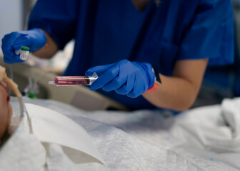 Nurse preparing syringe with red liquid for patient in hospital bed
