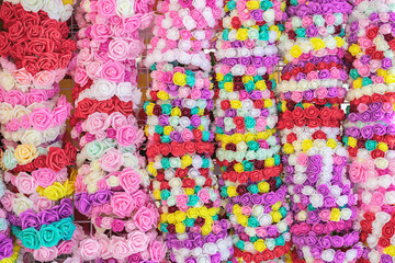 Rows of bright artificial rose garlands in vivid colors, outdoor craft display. Traditional festive decoration, annual rose festival in Bulgaria. Concept of festive mood, colorful decor, celebration