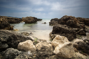 Beautiful rocky coastline in Mallorca under an atmospheric sky with calm sea reflecting the landscape at midday