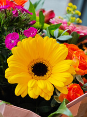 Bright yellow gerbera daisy among colorful flowers in a vibrant bouquet at a flower market in spring