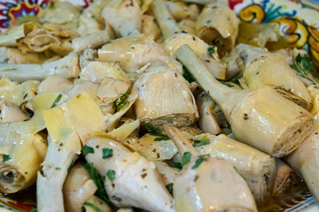 Marinated artichoke hearts with herbs in olive oil, served in a traditional ceramic dish, offering a Mediterranean appetizer full of flavor and texture.
