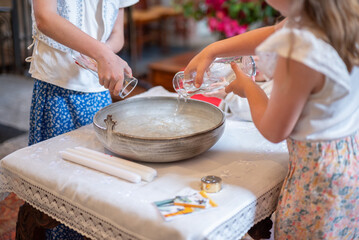 Des enfants qui versent l'eau bénite pendant une cérémonie de baptême dans une église
