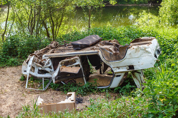 The body of a mangled and overturned car on the river bank