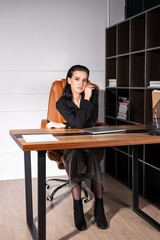 Woman sitting at a modern desk in a stylish office, engaged in work and deep thought during the day