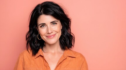 Smiling Woman with Dark Hair Against a Soft Pink Background