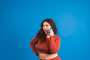 Plus size model having a surprising phone call on a blue background