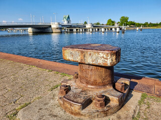 Naklejka premium Rusty mooring bollard overlooking drawbridge and river Schlei on sunny day