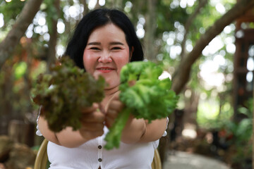 A joyful plus-size woman smiling warmly while holding fresh leafy greens in both hands,healthy living and natural foods