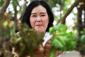 A joyful plus-size woman smiling warmly while holding fresh leafy greens in both hands,healthy living and natural foods