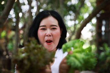 A smiling plus-size woman holding a wooden tray filled with fresh leafy greens,healthy living and natural food