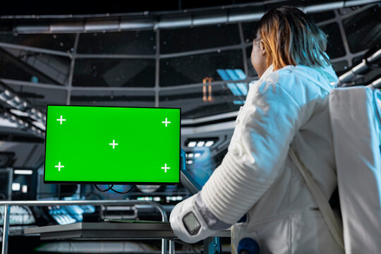 Female astronaut in spacecraft verifying navigation coordinates using green screen monitor. Woman in spaceship updating flight log on chroma key PC display during planetary exploration flight