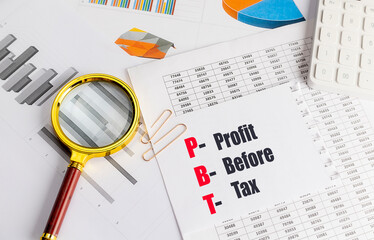 PBT profit before tax abbreviation on paper with charts, magnifying glass and calculator