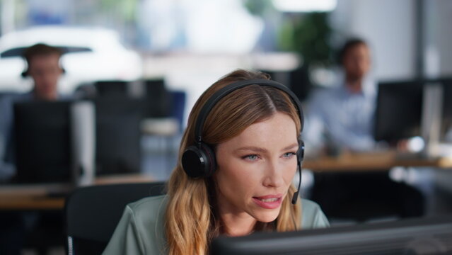 Help desk specialist talking on headset working computer at office closeup.