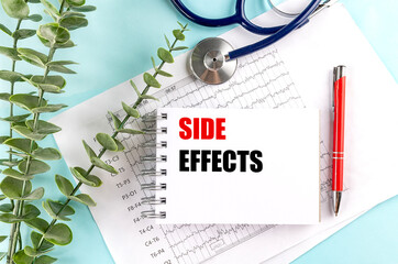 Side effects text on notepad with stethoscope, ECG printout, red pen and eucalyptus on blue background