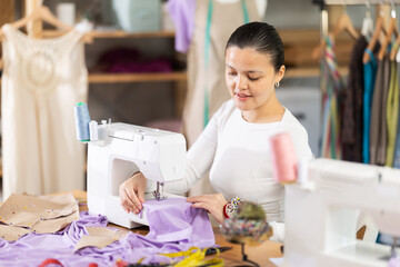 Asian woman works as a dressmaker in a workshop and sews clothes. Seamstress working on a clothing...