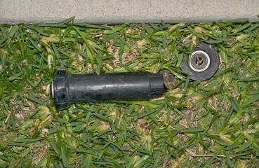 Broken sprinkler head nozzle on lawn from lawnmover accident backyard garden.