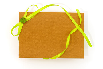 A textured brown envelope adorned with a long light wavy bright lime green ribbon bow and green...