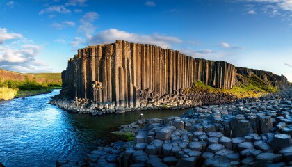 rugged terrain with towering basalt columns beside a riverbank