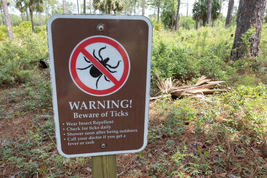 Sign warning about ticks at the trailhead in a park
