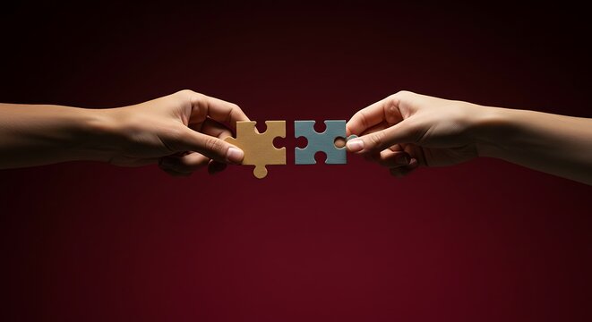 Connecting Puzzle Pieces: Two hands reach out, carefully aligning and fitting together puzzle pieces in this conceptual representation of teamwork and problem-solving.