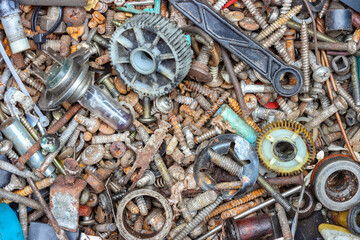A various rusty metal screws, tools, and mechanical parts in box, close up view