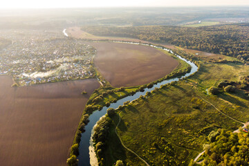 Aerial view of rural landscape with smoke from fires, meandering river going into the distance