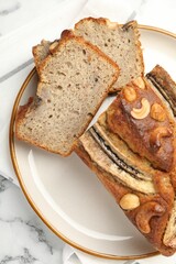 Cut banana bread with nuts on white marble table, top view