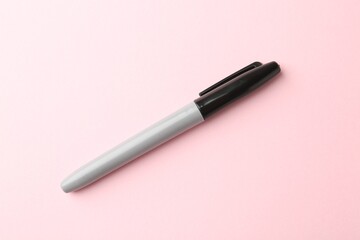 One black marker on light pink background, top view