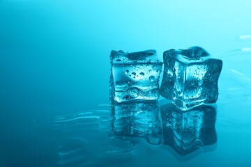 Cubes of clear ice on light blue background, space for text