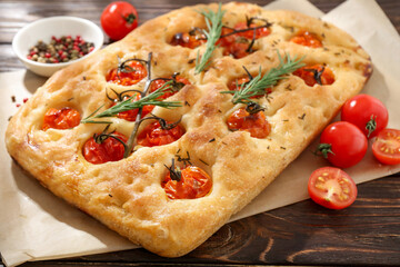 Delicious focaccia with tomatoes and spices on wooden table, closeup