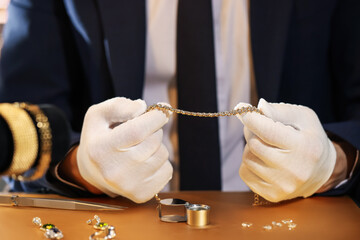 Appraiser working with luxury jewelry at table, closeup