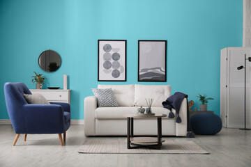 Stylish living room with comfortable sofa and light blue wall. Interior design