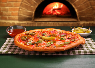 Freshly baked pizza on green wooden table against oven