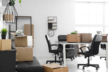 Interior of light office with cardboard boxes on moving day