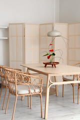 Dining table with beautiful ikebana in interior of room