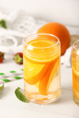 Fototapeta premium Glasses of infused water with orange slices on white table