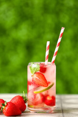 Glass of strawberry lemonade on grey tile table outdoors