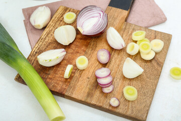 Wooden board and colander with different kinds of onion on white background
