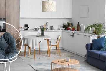 Interior of modern open plan kitchen with stylish sofa, armchair and coffee table