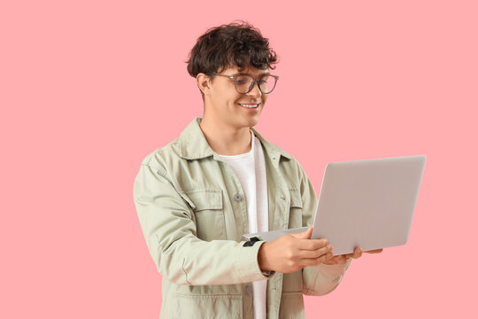 Male programmer with laptop on pink background
