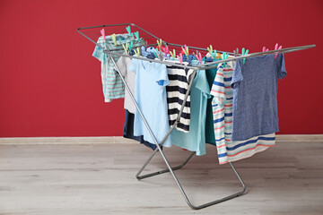 Clean clothes hanging on dryer near red wall