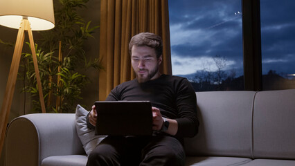 Man using tablet at night on sofa