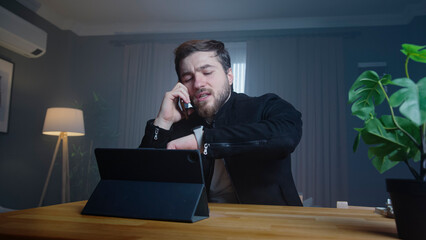 Busy businessman on phone checking time at desk