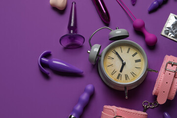 Alarm clock with different toys on purple background. Time for sex